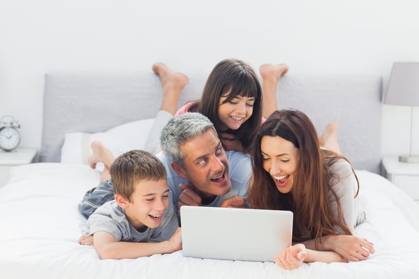 Cheerful family lying on bed using their laptop at home